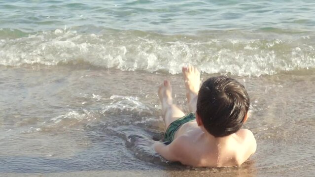 little preschooler boy having fun in sea ocean water sands beach sunny summer day naked child.kid in vacation with family swimming splashing water with hands and legs 4k real time video