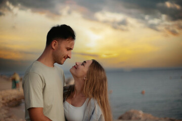 young couple in love at sunset by the sea walk along the seashore. Romantic trip to the resort.