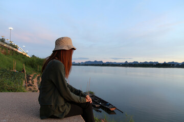 Asian woman sitting on the banks of the Mekong River in the morning, enjoying the fresh air.