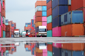 Forklifts handling freight, container boxes in logistic shipping yard with stacks of cargo containers in the background.