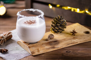 Christmas drink from raw eggs egg-nog on a wooden surface with a bokeh of rustic garlands