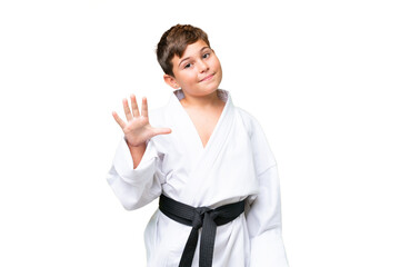 Little caucasian kid doing karate over isolated chroma key background counting five with fingers