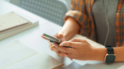 Education and literacy concept, College girl chatting with friend on smartphone after reading book