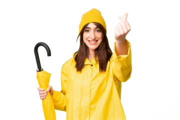 Young caucasian woman with rainproof coat and umbrella over isolated chroma key background making money gesture
