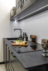 Several types of cheese with limes cut on a wooden board are located in the kitchen. Photographed with a low depth of sharpness from blurring