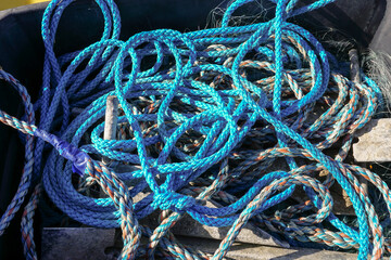 tangled sailing and fishing ropes by harbour. A messy pile of blue ropes.