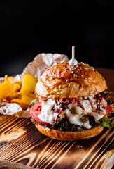 Traditional beef burger with cheese and vegetables on dark background