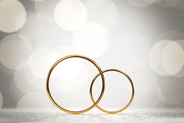 gold wedding rings for the wedding of the newlyweds stand side by side on a light background with brilliant bokeh. 3d render.