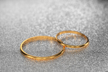 gold wedding rings for the wedding of the newlyweds lie on a light, shiny background. 3d render.