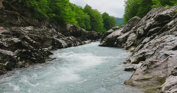 Aerial view of Mountain river and road. Flying over a mountain gorge. Slow motion 120 fps.