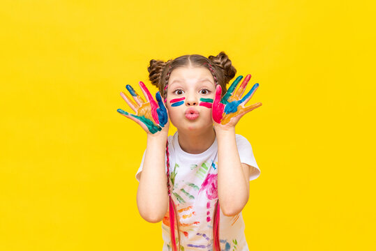 A little girl stained in multicolored paints is fooling around.  Children's creativity, drawing. Draw with your hands. The art of creating paintings for schoolchildren.