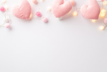 Fototapeta na wymiar Saint Valentine's Day concept. Top view photo of fluffy heart shaped toys light bulb garland and soft pompons on isolated white background with empty space