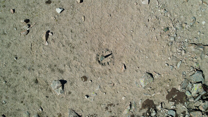 Drone view of a sundial made of stones. The shadow from the sun shows what time it is now. There are large stones lying around, moss grows in places. Sandy pass in the mountains. Kazakhstan