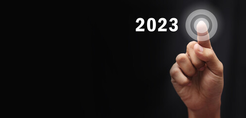 Finger pressing blue start 2023 button on virtual interface  with copy space for text. Concept of new year. Businessman pressing 2023 start up business. Beginning of New Year 2023