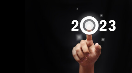 Finger pressing blue start 2023 button on virtual interface  with copy space for text. Concept of new year. Businessman pressing 2023 start up business. Beginning of New Year 2023