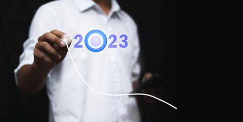 Finger pressing blue start 2023 button on virtual interface  with copy space for text. Concept of new year. Businessman pressing 2023 start up business. Beginning of New Year 2023