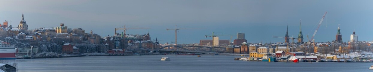 Fototapeta premium The bay Strömmen, the district Södermalm, old town Gamla Stan and wharf island Bleckholmen a snowy blech winter day in Stockholm