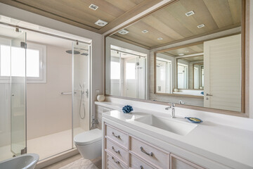 Luxurious bathroom with a large mirror with an unusual multiple reflection. Spacious shower area with glass railing. Daytime bright sunlight illuminates the huge bathroom, showing its splendor.