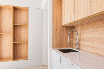 Modern kitchen with wooden furniture, gray countertop and built-in appliance in minimalist interior design