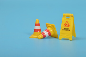 Repair In Progress sign and safety plastic cones isolated on a blue background