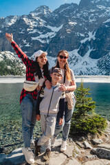 A family are standing on the shore of a lake. Morskie Oko, Tatras mountains.