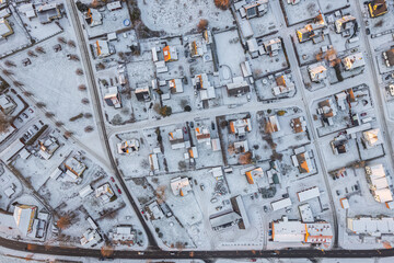 Aerial view on little European village in Sweden in winter, many private houses. Snowy weather, sunset. Warm sunlight. 