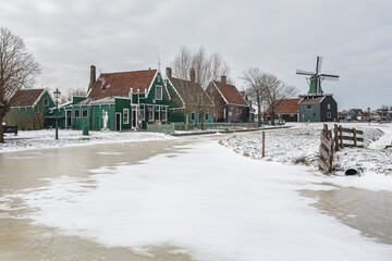 Winter landscape with frozen canal and traditional wooden house in Zaanse Schans, Netherlands - 554673122