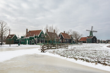 Winter landscape with frozen canal and traditional wooden house in Zaanse Schans, Netherlands - 554673152