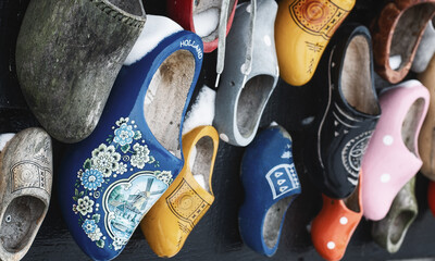 Colorful clogs against the background of a wooden wall. - 554673368
