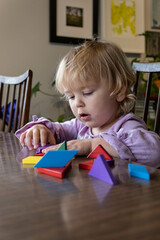 Two year old plays with tangrams; stacking and building with wooden toys