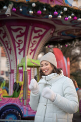 fair . attractions , carousel . girl dressed in a white jacket and a white hat. the girl smiles. .girl rejoices. emotions. Celebrating Christmas outdoors.
