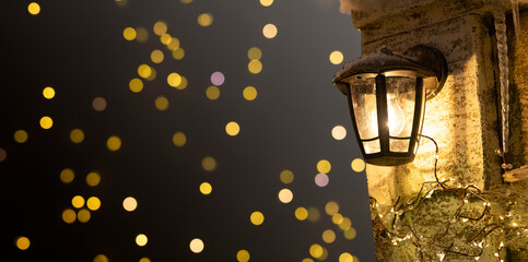 Street lantern, wall mounted yellow warm light in cold holiday winter. Banner, Christmas background
