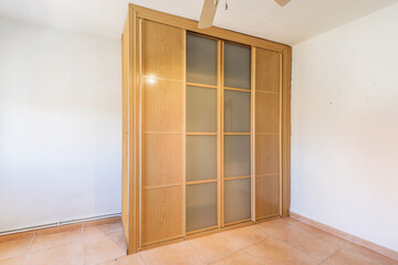A custom made wooden wardrobe with wooden and glass sliding doors in an empty room