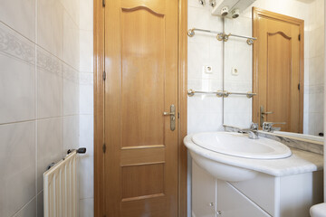 Fototapeta na wymiar A small bathroom with an aluminum radiator, a white bathroom cabinet with a mirror and a marble countertop and bars to hold towels