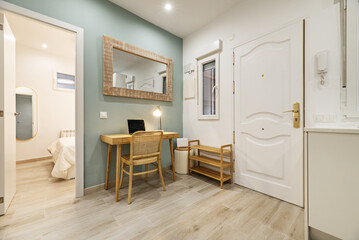Corner of a vacation rental with light wood furniture, green and white walls, and access to a bedroom