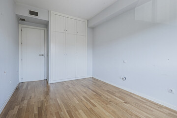 Room with light blue tones on the walls and built-in wardrobe with white doors with trunks and oak wood floors