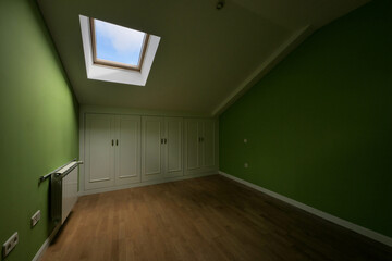 Room in the attic floor with ceilings with skylights and small closets with white doors in the wings