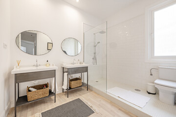 Designer closet with vintage white porcelain double sinks on metal cabinets and antique round mirrors, a walk-in shower with map glass and small white tiles