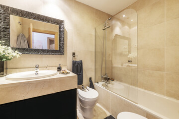 Bathroom with cream marble cabinets, glass-enclosed shower stall, and marble-framed mirror