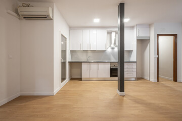 kitchen with newly installed white wooden cabinets, black countertop, exit to a terrace with glass door, metal pillar and wooden flooring