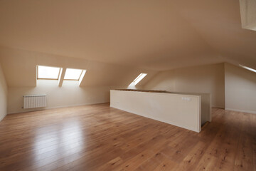 Empty attic with skylights on the eaves of the roof with floating chestnut wood flooring