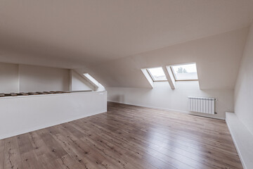 Attic of an empty single-family home with skylights on the eaves of the roof with chestnut floating flooring