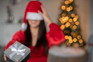 Lustige Frau mit Weihnachtsmütze über den Augen an Weihnachten. Bokeh von den Lichtern eines...