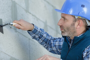 builder worker plastering facade of high-rise building with putty knife