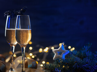 Two glasses of champagne or sparkling wine on a festive Christmas table with copy space. Blue...