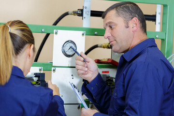 female and male worker checking the pressure gauge