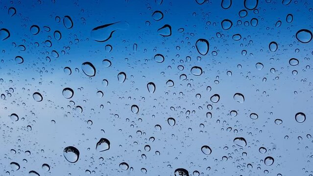Water droplets perspective through glass surface against blue sky good for multimedia content backgrounds
