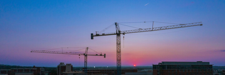 Fototapeta na wymiar Panorama Construction Crane over college campus with sunset dawn blue red purple skyline
