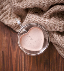 Heart shaped glass cup with cocoa and plaid on wooden background