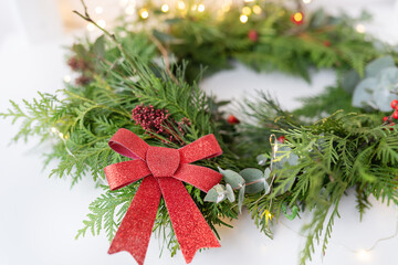 Stylish indoor Christmas wreath with a beautiful red bow, hang the wreath on the door. Festive atmosphere, beautiful bokeh in the background.